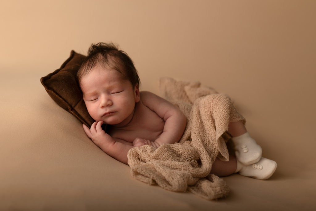 Portrait bébé couché sur le coté. avec ces petits chaussons.Photographe nouveau-né studio entre Toulouse et Montauban.